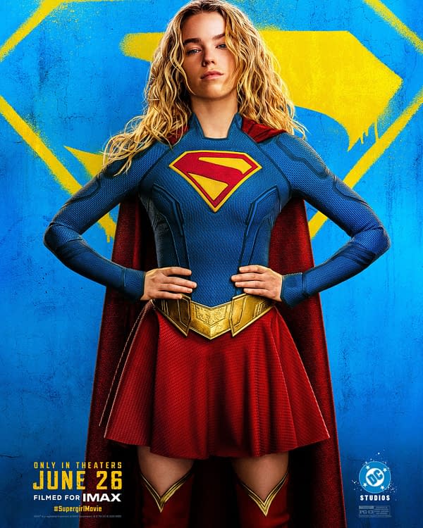 Supergirl movie poster showing a blonde superhero in a blue-and-red costume with the red-and-yellow S emblem, standing hands on hips against a bright blue background with a yellow symbol.