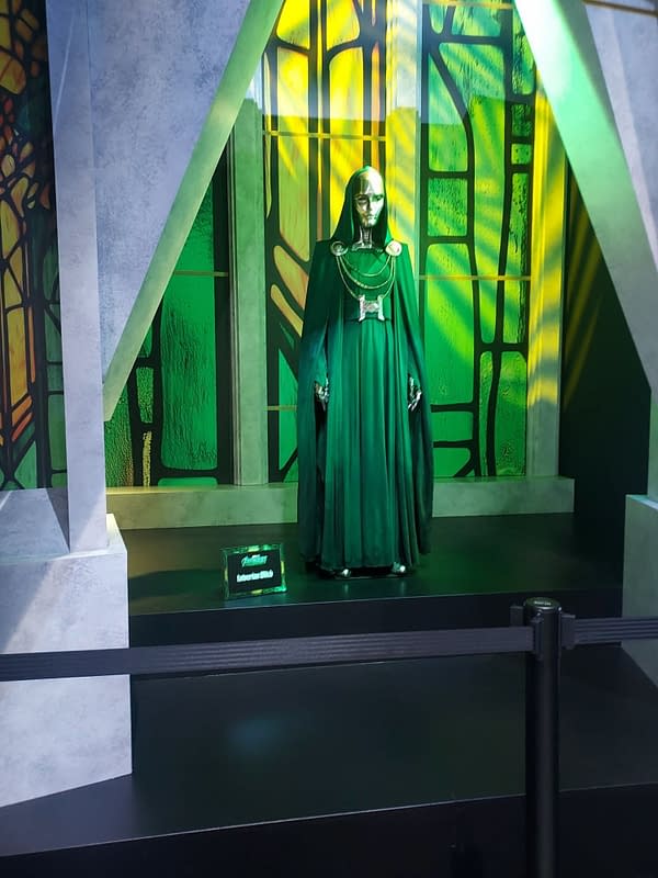 Green Doom-style costume display from Avengers: Doomsday at San Diego Comic-Con, with a masked figure in a long green cloak standing on a stage-like platform.