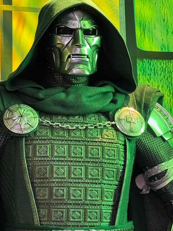 Close-up of Doctor Doom in a hooded green costume with a metal mask and ornate chest armor, likely from Avengers: Doomsday at SDCC.