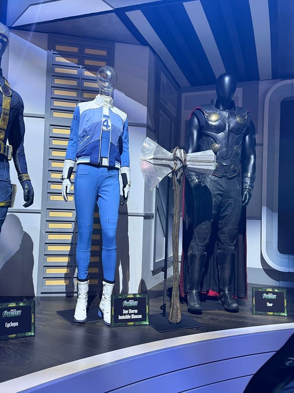 Marvel display at SDCC showing Avengers: Doomsday costumes for Cyclops, Sue Storm, Invisible Woman, and Thor, with a Sentinel prop beside them.