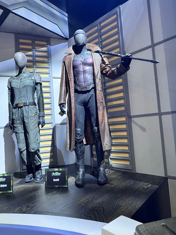 Avengers: Doomsday display of Gambit's costume at SDCC, shown beside another superhero outfit and a Sentinel-style figure holding a long staff.