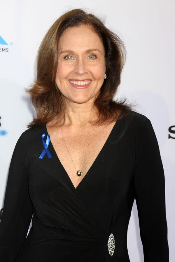 Erin Gray smiles at a Los Angeles event, wearing a black dress and a blue awareness ribbon.