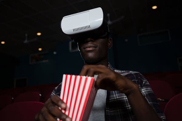 Man using a virtual reality headset while watching a movie in a theatre. By wavebreakmedia/Shutterstock